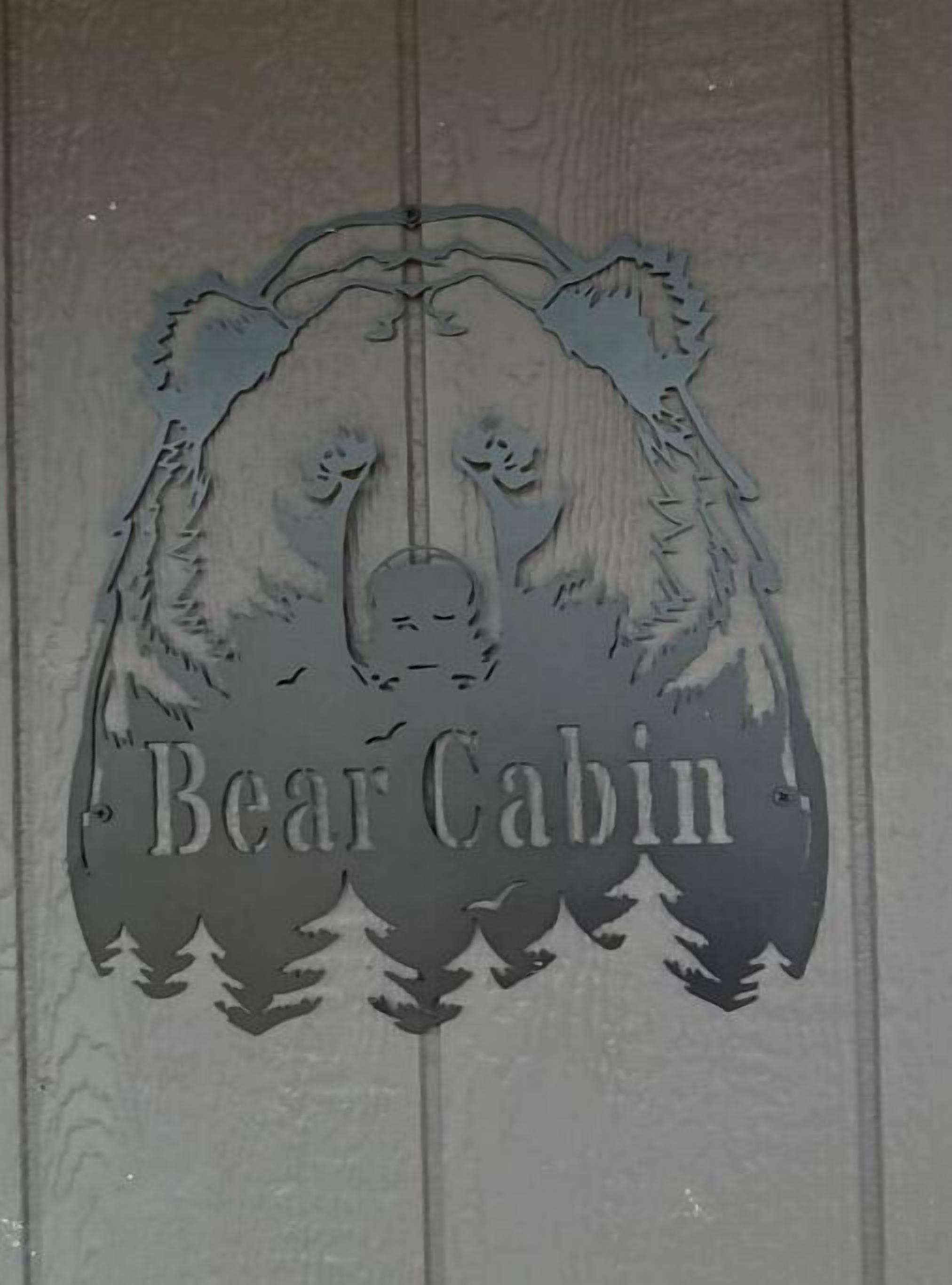 A wooden panel with a bear's head and the text "Bear Cabin".