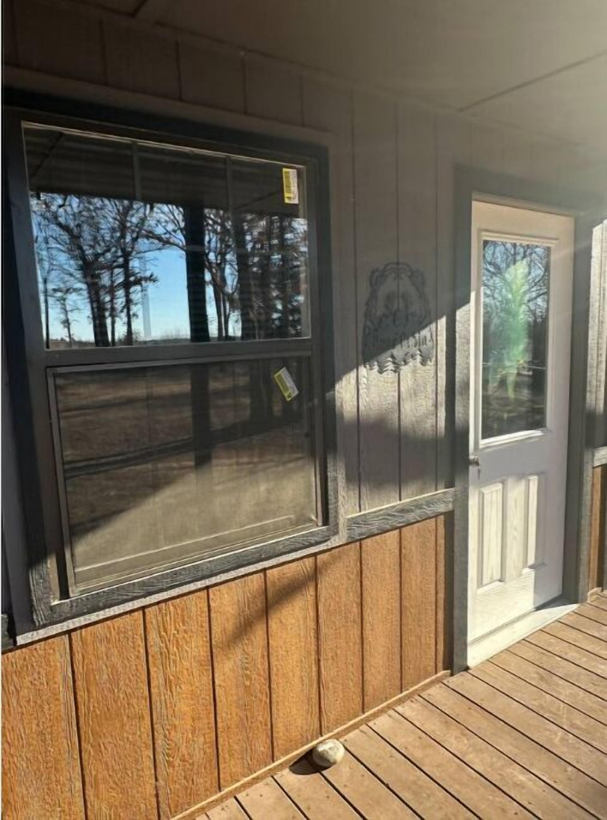 Une façade en bois avec une grande fenêtre et une porte blanche.