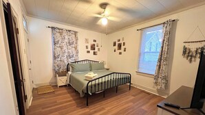 A bedroom with a bed, a ceiling fan, a window with curtains, and a wall-mounted TV. - Charming 2-bedroom apartment in beautiful Belleville with WiFi (Belleville)