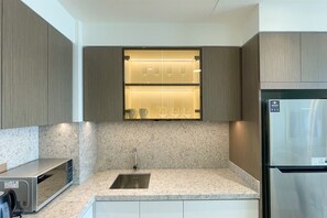 A modern kitchen with a built-in microwave, stainless steel refrigerator, and a granite countertop. - Beachfront 1BR Oasis & Stunning Views By Elie Saab (Dubai)