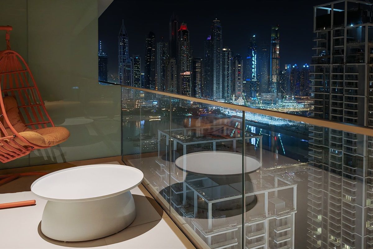 A modern room with a glass balcony overlooking a cityscape at night.