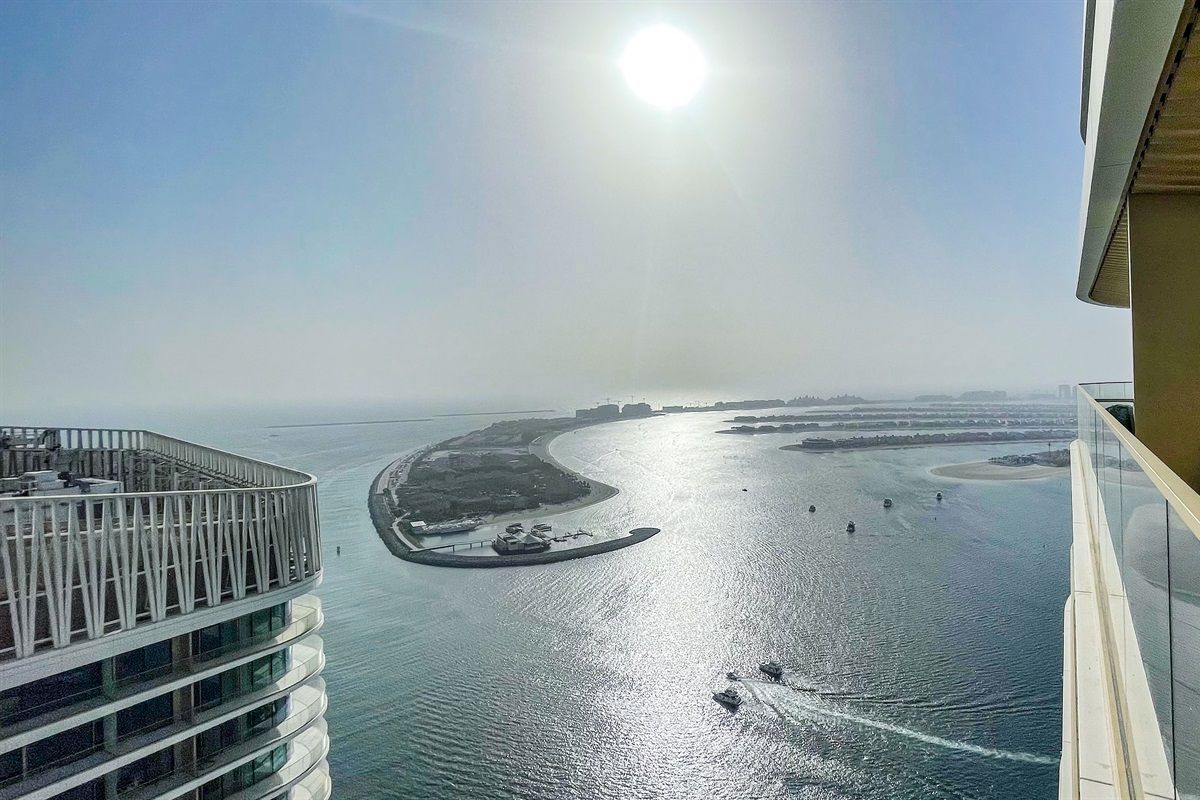 Um edifício alto com vista para um corpo de água, uma pequena ilha e um céu claro.