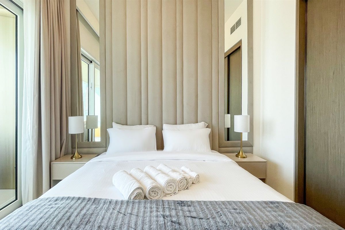 Une chambre d’hôtel avec un grand lit, deux tables de chevet et une fenêtre avec des rideaux.