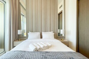 A hotel room with a large bed, two bedside tables, and a window with curtains. - Beachfront 1BR Oasis & Stunning Views By Elie Saab (Dubai)