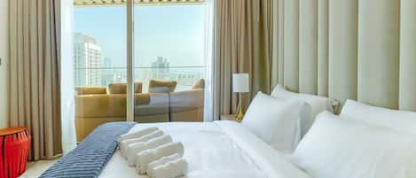 Quarto de hotel com uma cama grande, vista da cidade pela janela e varanda com assentos.