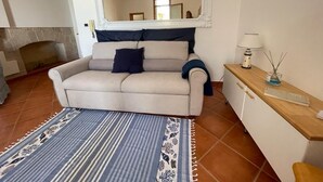 A living room with a sofa, a patterned rug, a mirror, a lamp, and a small table with a candle. - DIRECTLY OVERLOOKING THE HARBOR A FEW METERS FROM THE CATHEDRAL (Trani)