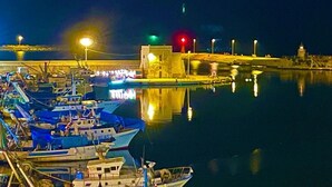 A marina at night with boats docked, a bridge in the background, and a building with lights. - DIRECTLY OVERLOOKING THE HARBOR A FEW METERS FROM THE CATHEDRAL (Trani)