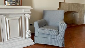 A room with a white fireplace, a striped armchair, and a framed picture above the fireplace. - DIRECTLY OVERLOOKING THE HARBOR A FEW METERS FROM THE CATHEDRAL (Trani)