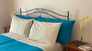 A bed with a metal frame, two pillows, a blue bedspread, and a wooden nightstand with a book and a lamp. - DIRECTLY OVERLOOKING THE HARBOR A FEW METERS FROM THE CATHEDRAL (Trani)