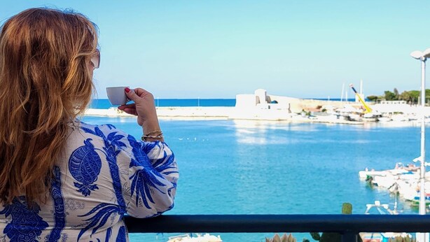 A person holding a cup, overlooking a marina with boats and a clear blue sky. - DIRECTLY OVERLOOKING THE HARBOR A FEW METERS FROM THE CATHEDRAL (Trani)