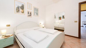 A bedroom with a bed, bedside tables, a nightstand, a mirror, and wall art. - Casa Vuvi - Two-room apartment very close to the beach. (Toscolano Maderno)