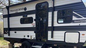 A Transcend One recreational vehicle with a sliding door, a step-up platform, and a logo for Grand A Design. - NEW 2025 RV, 1 Bedroom WiFi AC in Serene Winterport with Coast and Bangor nearby (Winterport)