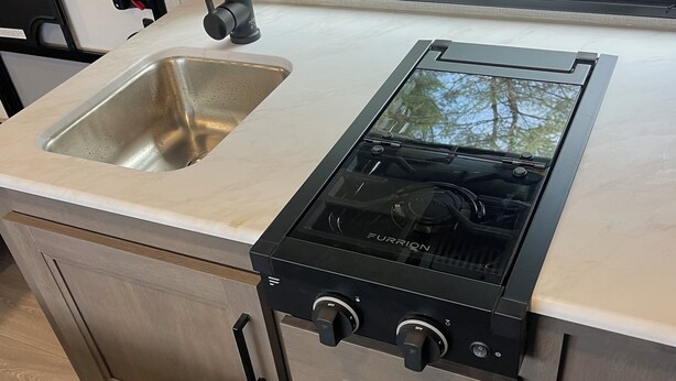A compact kitchenette with a stainless steel sink, a black Furrion stove, and a small oven. - NEW 2025 RV, 1 Bedroom WiFi AC in Serene Winterport with Coast and Bangor nearby (Winterport)