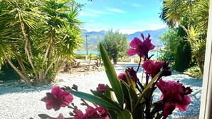 Ein Garten mit rosa Blumen, einem Kiesweg und Blick auf Berge im Hintergrund.