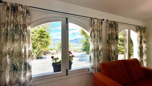 Ein Zimmer mit großem Fenster, Vorhängen und einem roten Sessel.