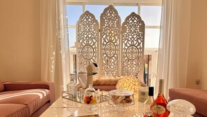Una sala de estar moderna con una mesa de centro de vidrio, una revista, objetos decorativos y vistas al exterior a través de un biombo.