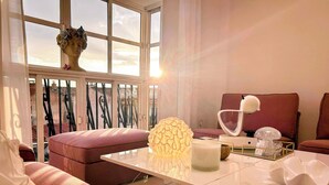 Una sala de estar moderna con un sofá, una mesa con objetos decorativos y vistas al exterior a través de amplios ventanales.
