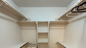 Et walk-in closet med åbne hylder, bøjlestang og en lille trillebør.
