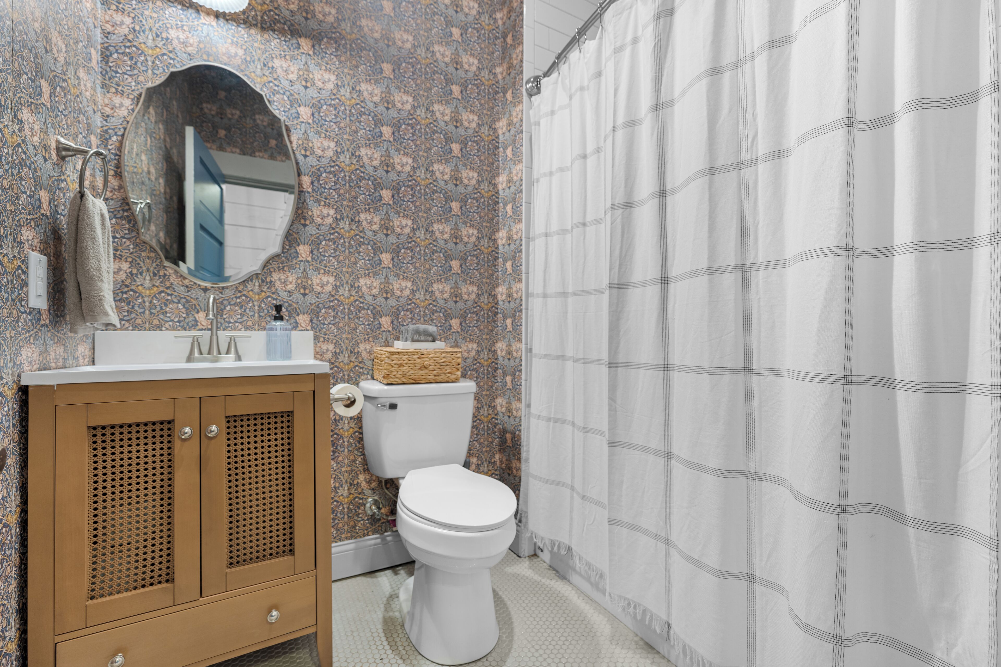 A bathroom with a toilet, sink, mirror, and shower curtain.