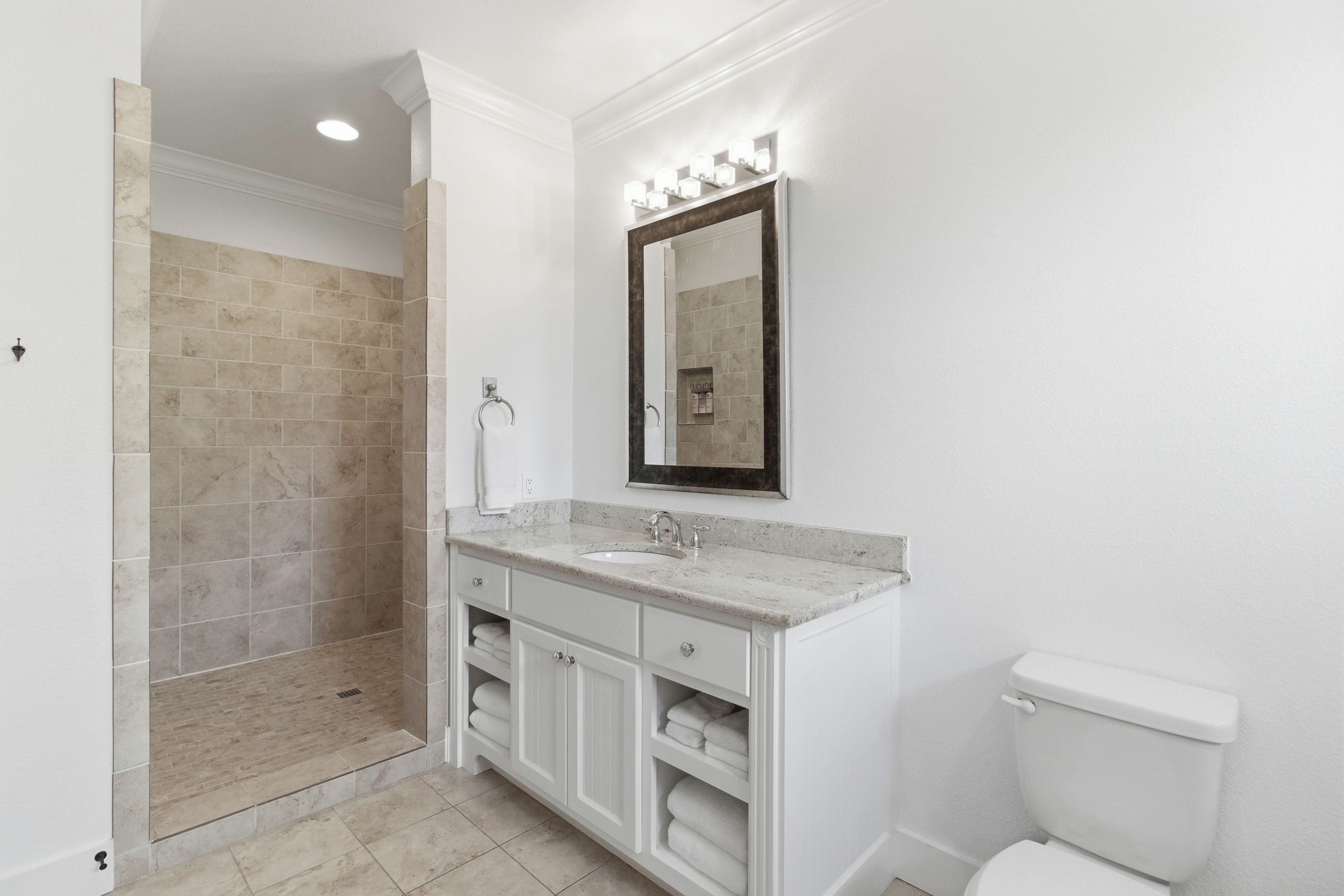 Une salle de bain équipée d’une douche, d’un lavabo, d’un miroir et de toilettes.
