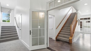 A modern interior with a staircase, a glass door, and a view of the outdoors. - Emigrant's Inn (Fredericksburg)