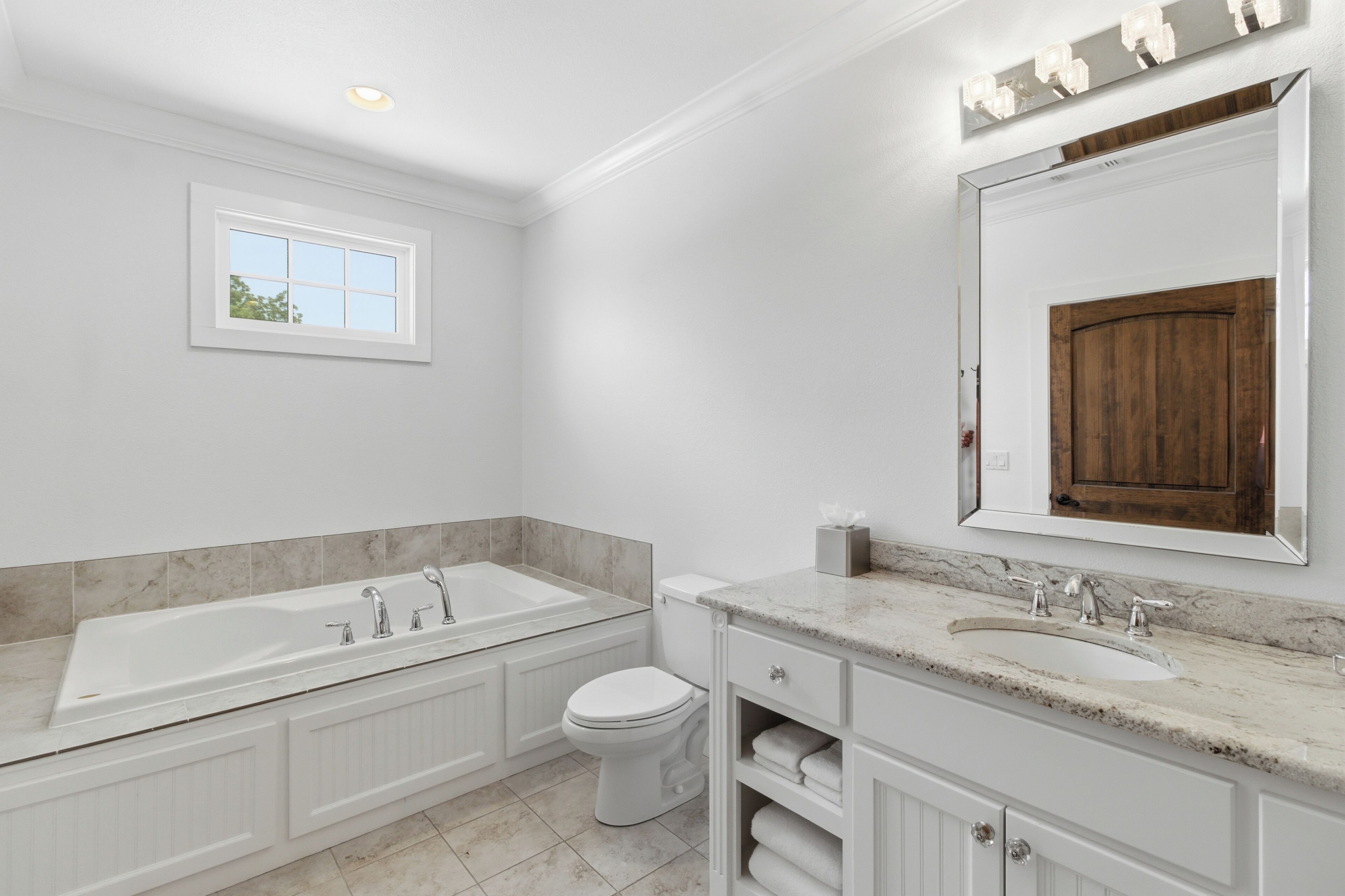 A bathroom with a bathtub, toilet, sink, and vanity.