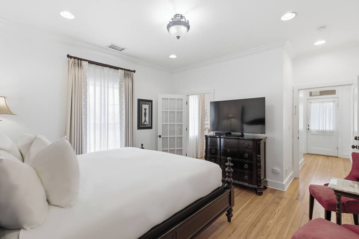 A bedroom with a large bed, a television, a dresser, and a chair.