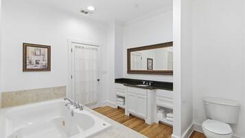 A bathroom with a bathtub, a sink, a toilet, and a mirror.