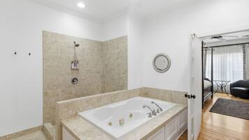 A modern bathroom with a large bathtub, a shower, and a mirror on the wall.