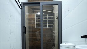 Un baño con ducha de vidrio, inodoro blanco y paredes con diseño de mármol.