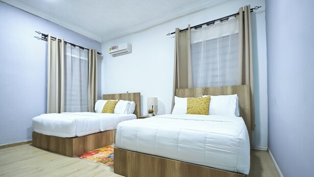 Habitación de hotel con dos camas, un cabecero de madera, una mesita y un equipo de aire acondicionado.
