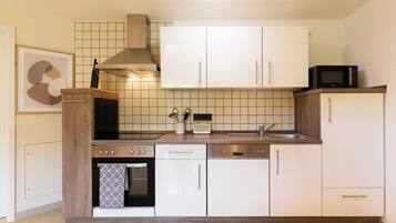 Eine moderne Küche mit weißen Schränken, einem eingebauten Backofen, einer Mikrowelle und einer Edelstahl-Dunstabzugshaube.