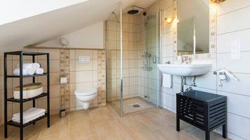 Ein modernes Badezimmer mit einer Glaskabine zur Dusche, einem weißen Waschbecken und einer schwarzen Ablage.