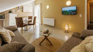 A modern living room with a sofa, a glass coffee table, and a television mounted on the wall. - Pension Memory (Bischofsheim an der Rhon)
