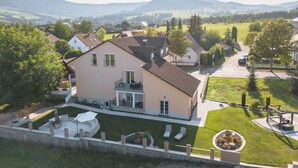 A large house with a spacious front yard, a covered patio, and a view of the surrounding countryside. - Pension Memory (Bischofsheim an der Rhon)
