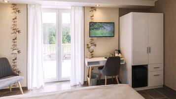 A hotel room with a bed, a desk with a chair, a television, and a wardrobe.