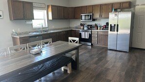 Une cuisine moderne avec des meubles en bois, des appareils électroménagers en acier inoxydable et un coin repas équipé d’une banquette.