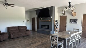 Un salon moderne avec une cheminée, une table à manger avec des chaises, un canapé et un ventilateur de plafond.