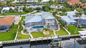 A large house with a swimming pool, a dock, and a marina.