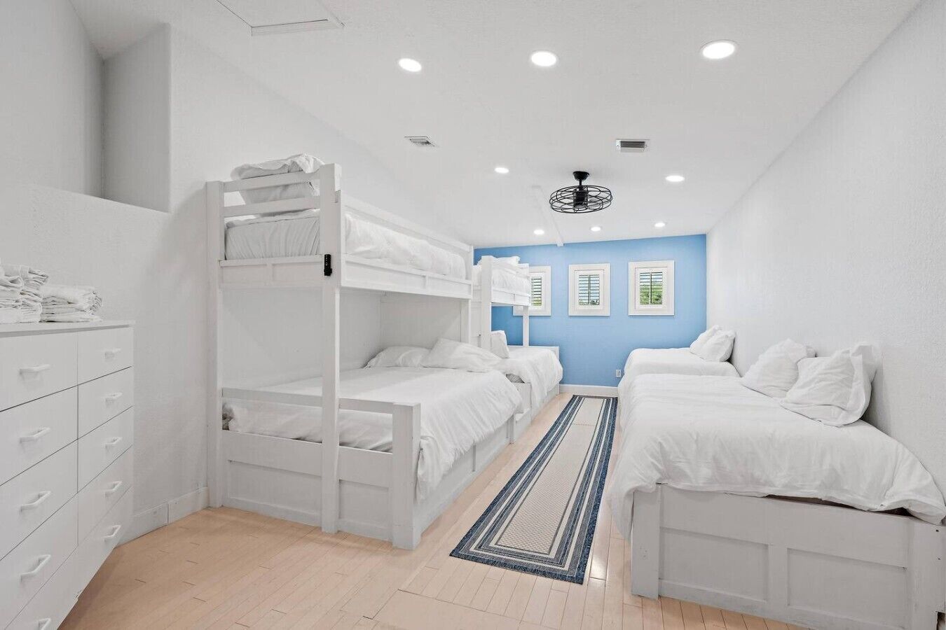 A room with bunk beds, a dresser, and a blue accent wall.