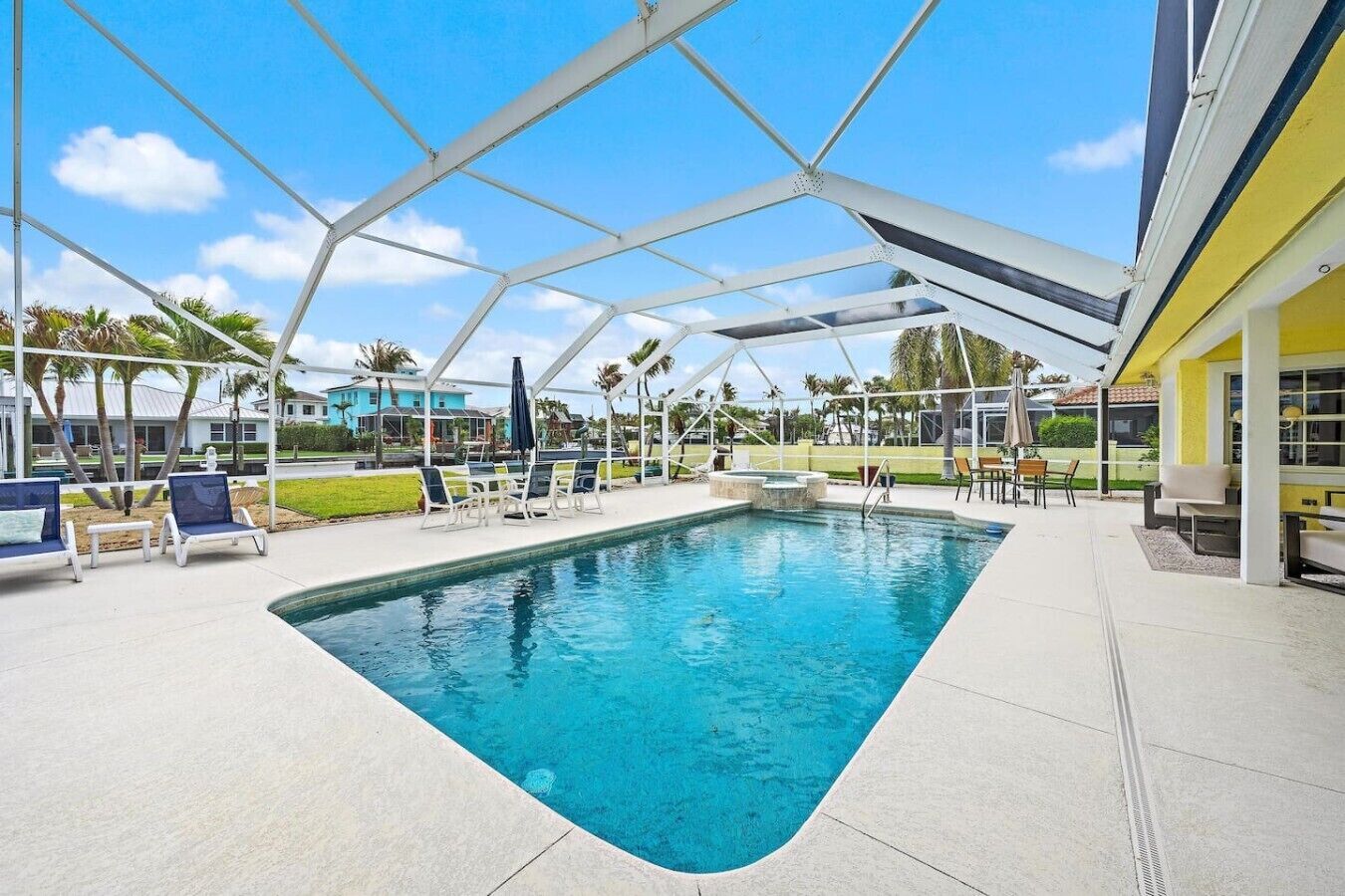 A swimming pool with a covered area, lounge chairs, and a view of the surrounding landscape.
