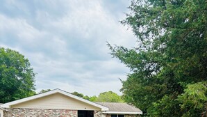 A two-story house with a garage and a small attached shed. - Poseidon’s Big Getaway – 3BR/2BA Surrounded by Nature, Minutes from the Beach! (Kitty Hawk)