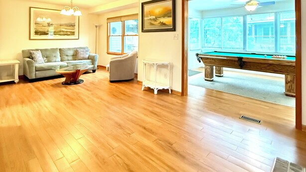 A spacious living room with hardwood flooring, a pool table, a sofa, and a ceiling fan. - Poseidon’s Big Getaway – 3BR/2BA Surrounded by Nature, Minutes from the Beach! (Kitty Hawk)