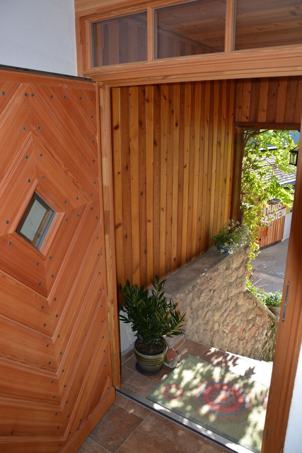 A wooden entrance with a stone ledge, potted plants, and a door with a geometric design. - Apartments with Breathtaking Lake Views, 300 meters from the Center of Hallstatt. (Hallstatt)