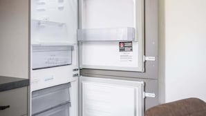 A refrigerator with multiple shelves and drawers, a power outlet, and a wall-mounted artwork.