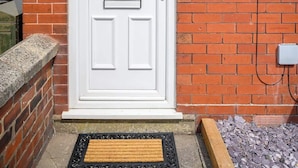 A white front door with a small window above it, a mailbox, and a number plate '35' on the brick wall.