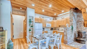 A kitchen with wooden cabinets, a brick fireplace, and a dining table set for six.