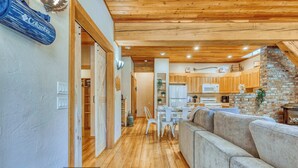 A spacious living area with a wooden ceiling, a large sofa, and a dining table with chairs.