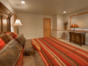 Une chambre à coucher avec un lit, un canapé, une porte en bois, une armoire et une lampe.