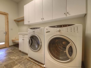 A laundry room with two front-loading washing machines and a cabinet above them.